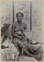 Studio portrait of woman with fan next to tea set