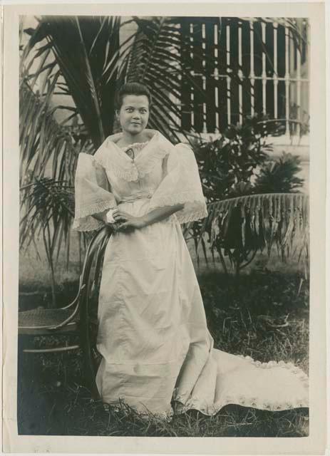 Woman in dress beside chair and tree