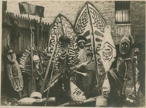 Collection of carved shields, figures, poles, weavings