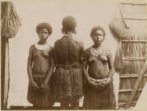 Three women tattooed and adorned with ornaments