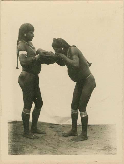 Two men demonstrating the Woyawoi method of giving a drink