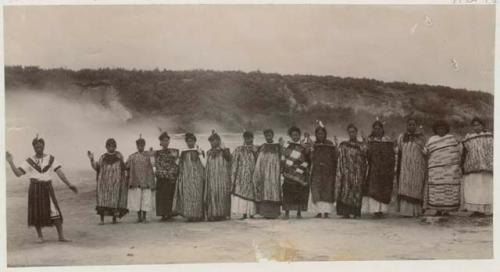 Women standing in line with one hand raised, one with infant