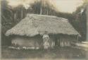 Woman in front of building with thatched roof