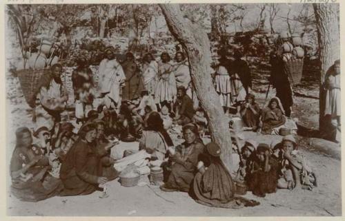 Group of men, women, and children outside, some spinning