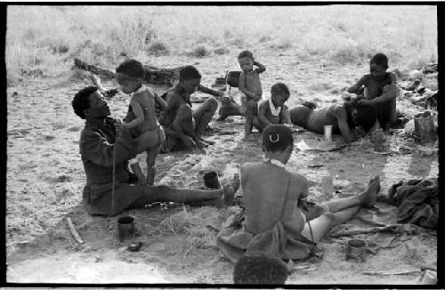 ≠Toma bouncing !Ungka Norna on his lap, sitting with a group of people