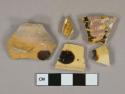 Black on yellow slip decorated earthenware vessel body and rim fragments, buff paste