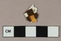 Brown and yellow on white slip decorated earthenware vessel body fragment, checkerboard pattern, likely annular ware, white or light buff paste