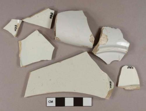 Undecorated white pearlware vessel body, rim, and base fragments, white paste