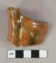 Yellow on red slip decorated lead glazed redware vessel rim and handle fragment, red paste
