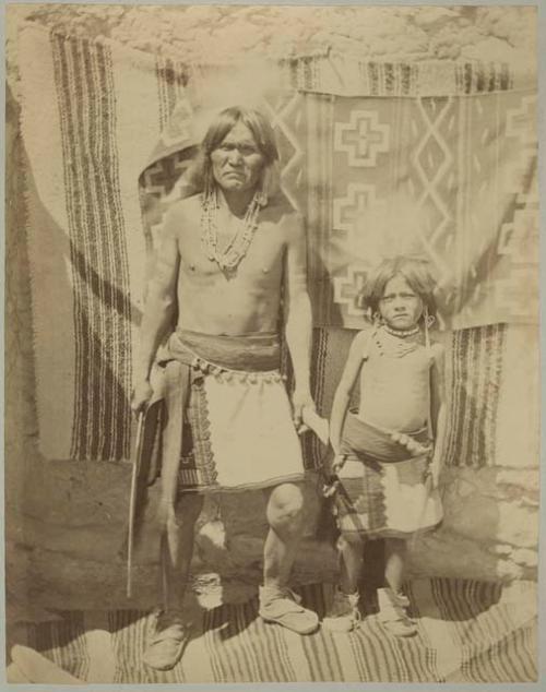 Hopi man and child with equipment for hunting rabbits