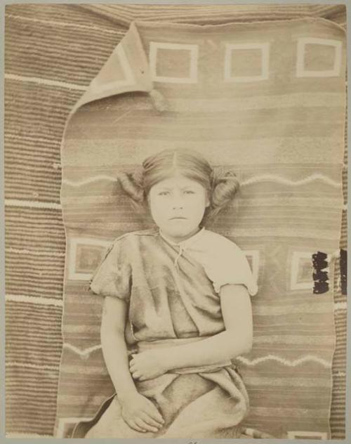 Hopi girl sitting in front of woven mat