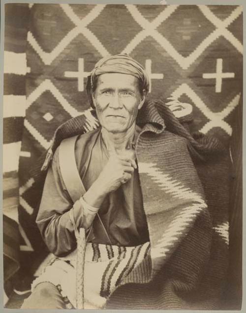 An old Navajo photographed with a blanket over his shoulders