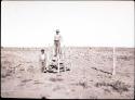 Two Hopi men standing with fence and stile