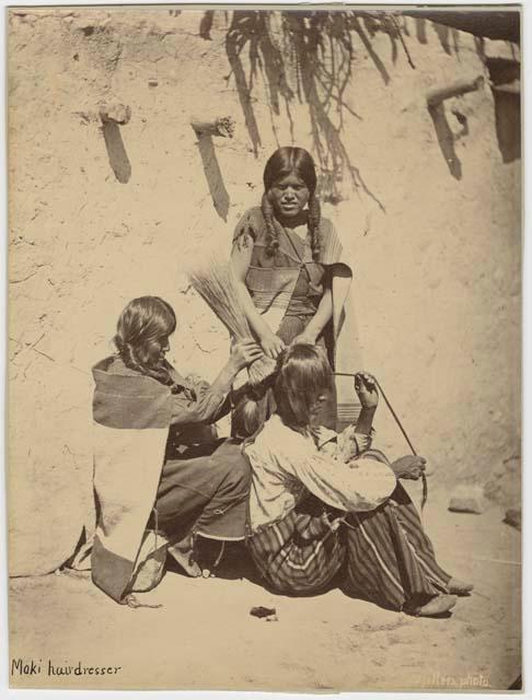 Two Hopi women styling another person's hair