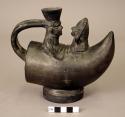Ceramic spout and handle bottle, horn-shaped base with 2 human figures. Blackwar