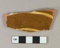 Yellow on brown slip decorated redware vessel body fragment, red paste