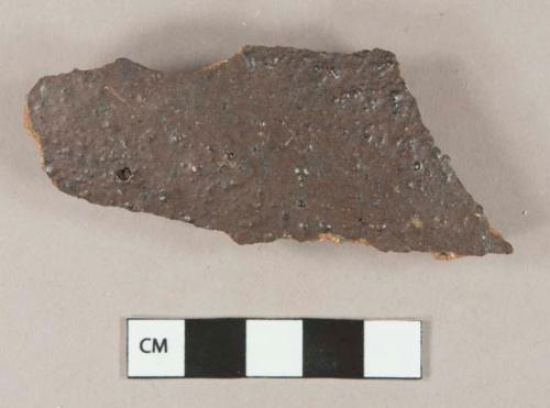 Dark lead glazed redware vessel body fragment, visible temper