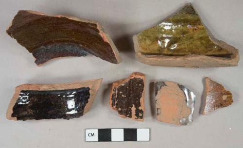 Black and brown lead glazed redware vessel body and base fragments, red paste