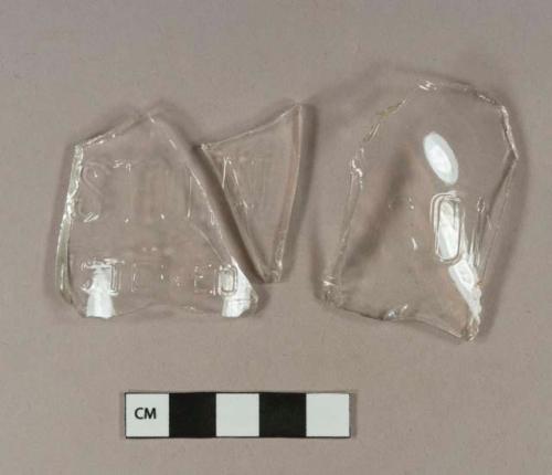 Colorless bottle glass fragments; one embossed with "SO[N or M]"; two fragments refit, embossed with "STON / ISTERED"