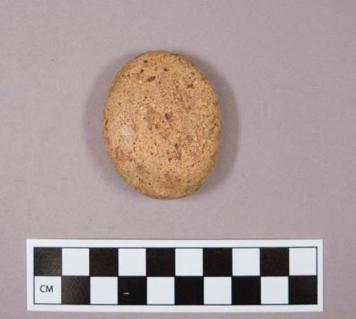 Flint, 1 round smooth stone, flattened, indent on one side, reddish tan