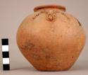 Small slipped red sandy ware vessel with a "ramshorn" decoration made of hollow