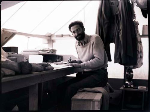 Man in beard (Dick Wheeler?) in tent, working