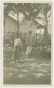 Photograph of woman, baby, man, standing,  elderly woman seated