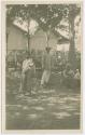 Photograph of woman, baby, man, standing,  elderly woman seated