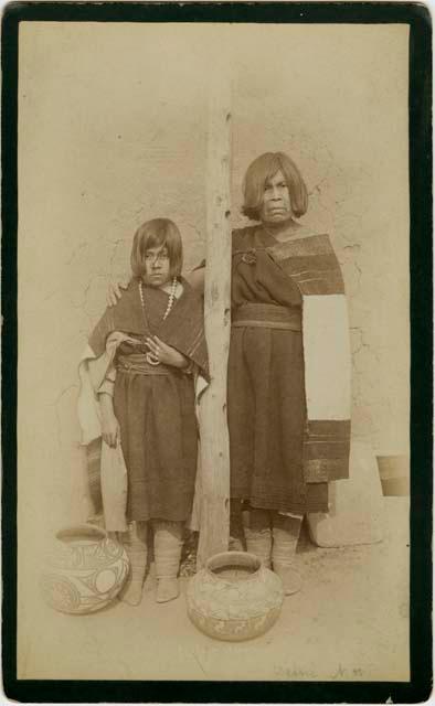 Woman and girl standing next to post