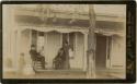 Two men, two women and a baby on porch in front of house