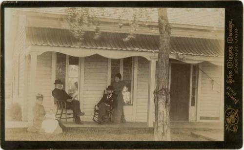 Two men, two women and a baby on porch in front of house