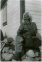 Man sitting against house