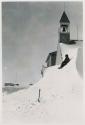 Person sitting on snow drift against church