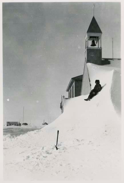 Person sitting on snow drift against church