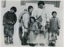 Family standing in front of snowdrift against building