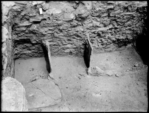 Room 499, north wall. Two upright slabs in floor.  Mealing bins?