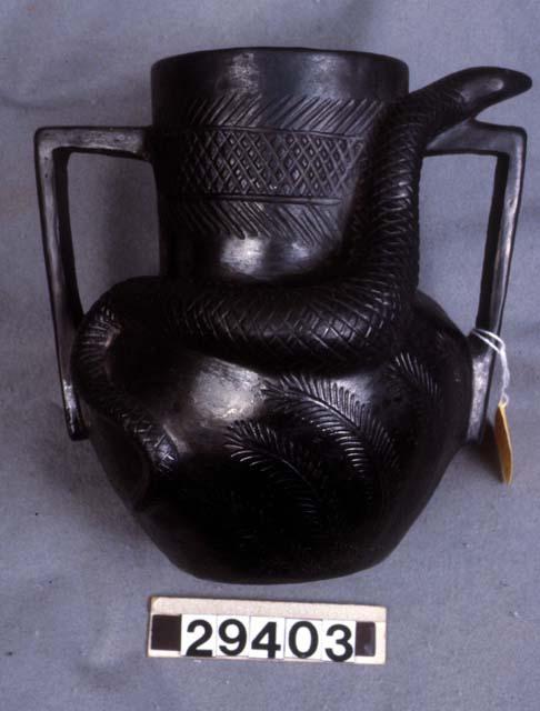 Black pot with two handles and modelled snake and incised lines on side