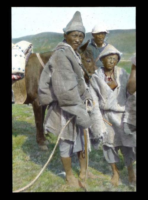 Lantern slide of three people standing with horse, hand-colored