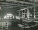 Peabody Museum storage with canoes, glass cases, and frames