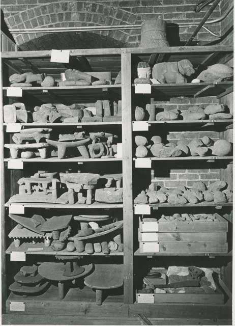 Historical photograph of Peabody Museum attic storage shelf with various stone objects