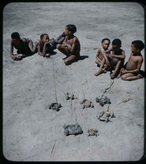 Toys: Group of boys sitting, with toy cars in the foreground