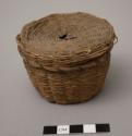 Small covered sweetgrass basket with faded dyed splints; splints damaged at top