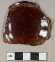 Amber glass vessel base fragment, letter "B" embossed at center