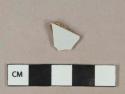 Undecorated white tin-glazed earthenware vessel body fragment, buff paste