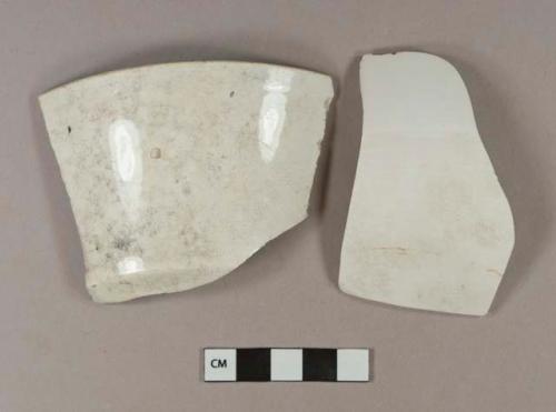 Undecorated porcelain body sherd, partially unglazed. Undecorated whiteware rim sherd