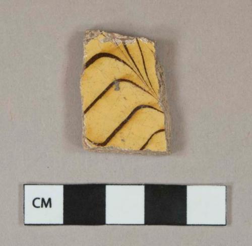 Yellow and dark brown combed slip glaze earthenware vessel body fragment, buff paste