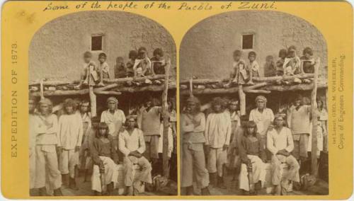 Group of men and children in front of a structure