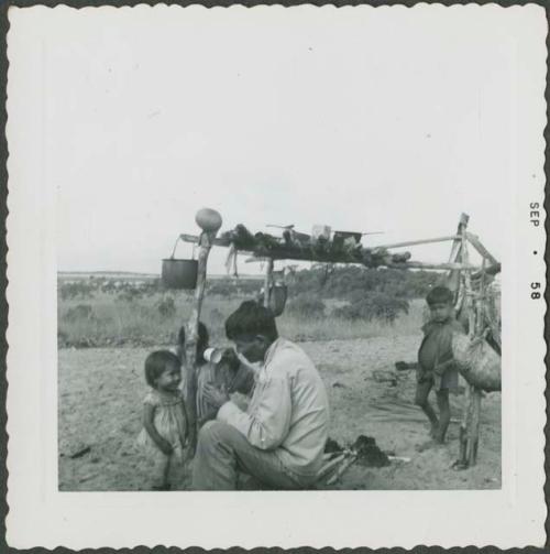 Photograph album, Yaruro fieldwork, p. 42, photo 2, man holding cup with children around