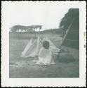 Photograph album, Yaruro fieldwork, p. 58, photo 4, Yaruro sitting on the ground wrapped in a blanket