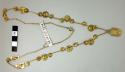 Gold necklace of tubular beads, discs, and fob with punctate design
